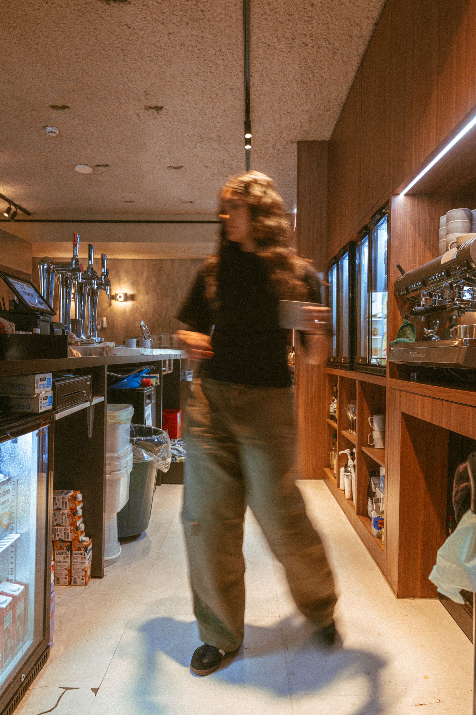 Behind the bar at Claw, a barista walking past the coffee machine