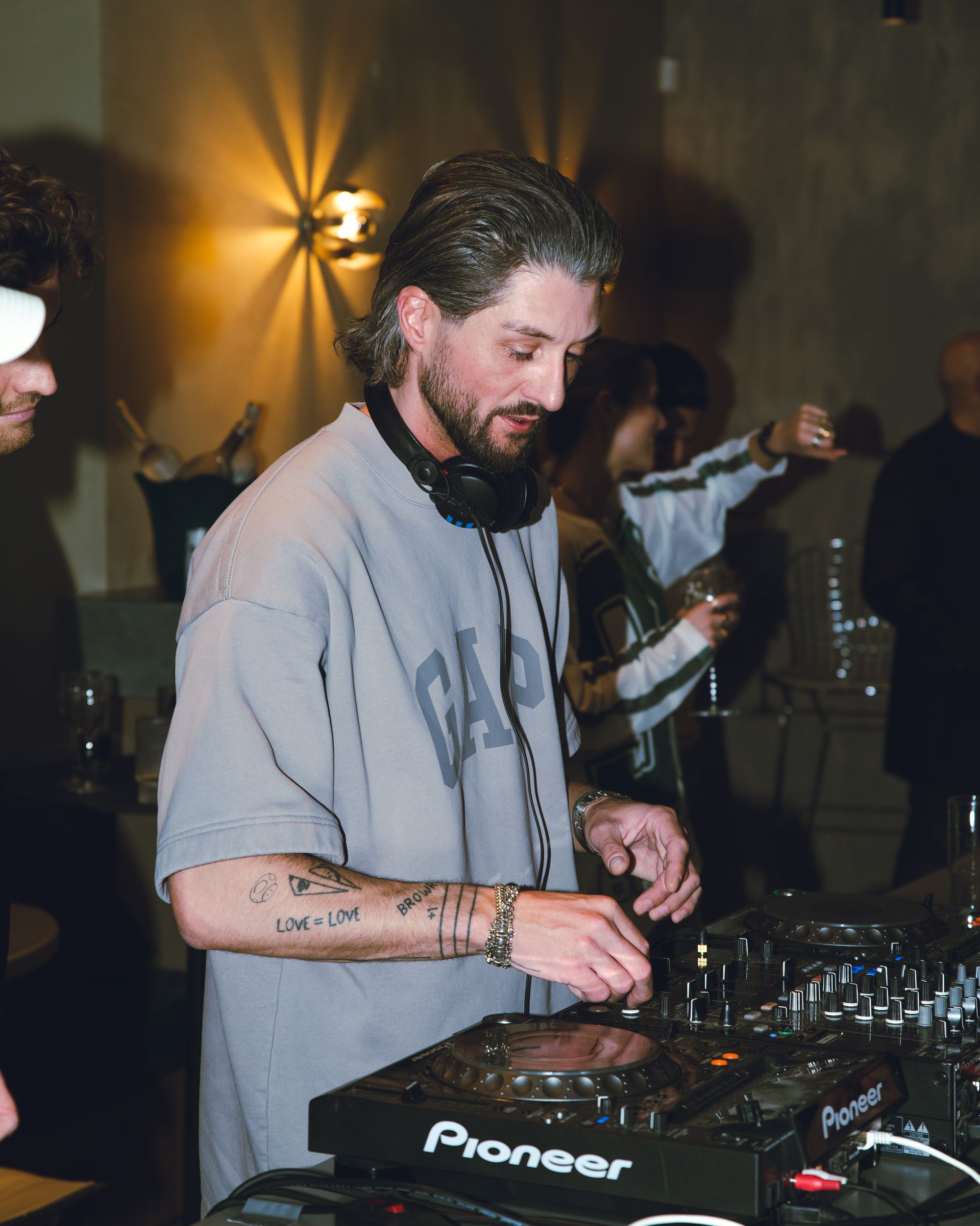 A DJ playing under the wall lamp at a Claw night